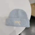 Soft light blue bouclé knit beanie featuring a delicate white embroidered bow detail - One Size / Light Blue