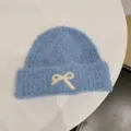 Detail view of a cozy light blue knit beanie featuring a cute white ribbon embroidery - One Size / Blue