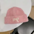 Detailed view of soft pink knit beanie featuring a cute embroidered cream bow detail - One Size / Grapefruit Pink