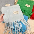 Primer plano de bufandas de lana bouclé de colores con borlas y etiquetas de tela - 222cm / Azul claro