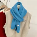 Detail van blauwe gebreide wollen sjaal met decoratieve schelpknoop en handmade label - 165cm / Hemelsblauw
