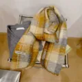 Dettaglio di una sciarpa di lana a quadri elegante con consistenza morbida e cuciture. - Agata Gialla