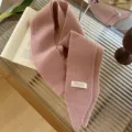 Primer plano del tejido de punto rosa suave y la etiqueta Trendy de una bufanda estrecha - 185x8cm / Rosa