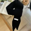 Vista detallada de una elegante bufanda de punto estrecha negra con etiqueta blanca Trendy - 185x8cm / Negro Clásico