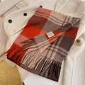 Close-up of a warm 100% wool checkered scarf with fringe detail on a beige coat - 180cm / New Year Red Plaid