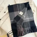Macro view of a classic plaid wool scarf with fringe detailing on a beige coat. - 180cm / Black & Gray Plaid