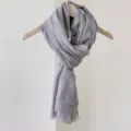 Vista dettagliata di sciarpa in cotone e lino grigio fumo con frange su appendino in legno - 180cm / Grigio Fumo