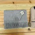 Detailed view of 100% Australian wool grey scarf with tassel fringe on wood background - Marl Grey