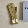 Close-up of mustard yellow knitted wool gloves with a decorative white cloth label. - One Size / Avocado Green