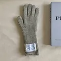Close-up view of grey knitted wool gloves with a white vintage-style fabric label - One Size / Gray