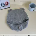 Detailed view of a soft grey knitted winter hat featuring cute bear ears and a heart button - Gray