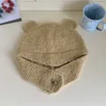 Detailed macro view of beige knitted bear ear hat featuring heart-shaped button decor - Rice Camel