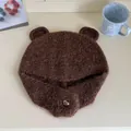 Close-up of a brown fluffy bear ear knitted hat with a small silver heart detail - Brown