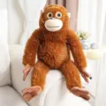 Süßer brauner Plüsch-Oran-Utan mit langen Armen auf weißem Sofa als Geburtstagsgeschenk - Hellbraun / 30cm