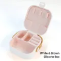 Portable white jewelry box with pink interior compartments and brown leather strap - Silicone Earring Box / 9CM*9CM*3.9CM / White