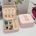 Joyero de viaje rosa portátil con un parche bordado de la letra I elegante. - Letra I / 10x10x5cm