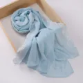 Primer plano del delicado borde de encaje floral blanco en un chal de gasa azul claro. - 180cm / Aguamarina