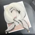 Close-up detail of a white French style gauze scarf featuring tweed trim and pearl pendant - 68cm / White