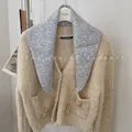 Detail view of a stylish wool knit triangle scarf paired with a beige teddy bear cardigan. - 81cm / Gray