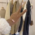 Close-up detail of brown knitted glove featuring plush white faux fur cuff and pink brand label - One Size / Mocha Coffee
