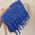 Detailed macro view of thick blue wool-blend scarf with embroidered girl and tassels - Embroidered Girl / Sapphire Blue