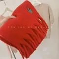 Macro view of a thick red wool blend scarf featuring unique girl embroidery and fringe detail. - Embroidered Girl / Red