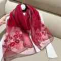 Detailed view of red silk blend scarf with elegant floral embroidery and gold trim - 180cm / Burgundy
