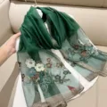 Detailed view of elegant floral embroidery and gold metallic edge on green silk scarf - 180cm / Emerald
