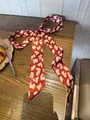 Rode en witte zijden sjaal met koeienprint als haarstrik op een houten tafel - 140cm / Elegant Rood Luipaardprint