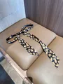 Detailopname van een zijden haarlint met luipaardprint geknoopt in strik op leer - 140cm / Koffie Luipaardprint