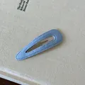 Primo piano di un fermaglio per capelli in tessuto azzurro con cuciture a vista fini - Tinta unita / Goccia D'acqua Blu