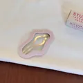 Détail d'une pince à cheveux BB rose à pois en forme de nuage sur un tissu blanc doux. - Style Nuage Évidé / Rose à Pois