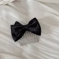 Close-up detail shot of elegant black satin polka dot bow hair comb on pleated white fabric - Bow Hair Comb / Black Polka Dot