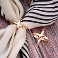 Detaillierte Nahaufnahme eines eleganten goldenen X-förmigen Seidenschal-Rings - Gold