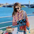 Woman wearing a vibrant geometric pattern ethnic scarf with blue tassels by a river. - Style 267