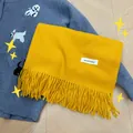 Bright yellow soft knit scarf with long tassels and minimalist white brand tag - Turmeric