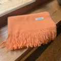 Premium soft orange winter scarf with elegant tassel fringe detail on a wooden texture background - Orange Pink