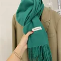 Cozy emerald green winter scarf featuring classic tassels and white decorative label - Green
