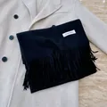 Soft solid black scarf with elegant tassel detail and minimalist woven brand label - Black