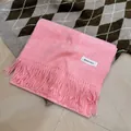 Premium soft pink winter tassel scarf with brand label on a checkered knit background - Marl Watermelon Red
