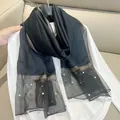 Detail shot of black faux silk scarf featuring pearl accents and gold metallic trim. - 180cm / Black
