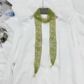 Macro detail of green floral lace hair ribbon featuring elegant golden lobster clasps. - Fan Pendant Style / Olive Green
