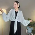 Detailaufnahme eines hellblauen Pailletten-Chiffon-Schals mit eleganten Laternenärmeln. - Einheitsgröße / Blassgrün