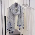 Elegant blue geometric pattern scarf with tassels displayed on a clothing rack hanger - Blue Fretwork / 180cm