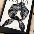 Detail view of a black and white paisley silk scarf on a fashion magazine backdrop - 70cm / Black Paisley Four-Grid