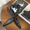 Detailed close-up of a pleated black and white paisley silk-feel scarf with a gold ring. - Pleated Square Scarf (With Scarf Ring) / 70cm / Black Paisley