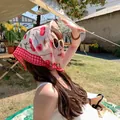 Detailed view of a cotton linen square head scarf with cherry print and red checkered border - Beige Cherry