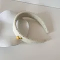 Detailopname van een crème gewatteerde haarband met zwarte stippen en geel knoopje - Knoop Hoofdband / Gele Stippen