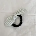 Detalle de un coletero con lazo de cuadros verde y blanco y base de goma negra. - Goma para Pelo a Cuadros Verde