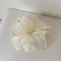 Nahaufnahme eines elfenbeinfarbenen Organza-Scrunchies mit eleganten Kunstperlen-Akzenten. - Perlen-Netz-Haargummi / Gelb